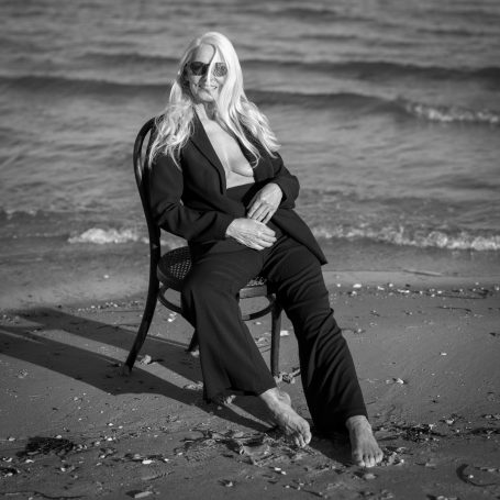 Model im Anzug auf Stuhl an Ostsee